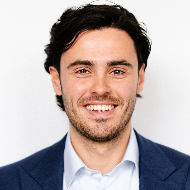 Smiling man in a blue suit with a white background.